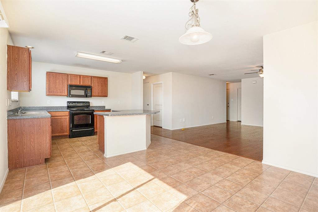2120 Bliss Road Fort Worth, TX 76177 - Photo 11 of 25 Kitchen with a kitchen island, black appliances, light tile patterned floors, and a ceiling fan