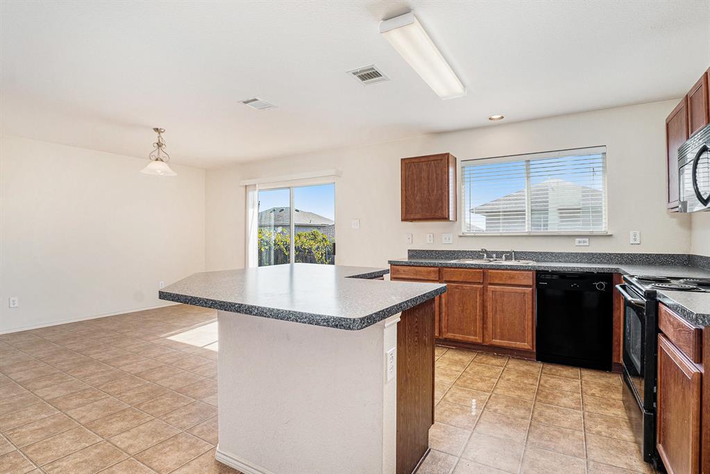 2120 Bliss Road Fort Worth, TX 76177 - Photo 12 of 25 Kitchen featuring dark countertops, black appliances, a center island, wood finish cabinetry, and light tile patterned floors