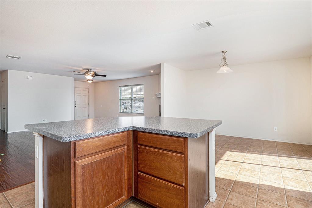 2120 Bliss Road Fort Worth, TX 76177 - Photo 25 of 25 Kitchen featuring a kitchen island, open floor plan, light tile patterned floors, wood finish cabinetry, and hanging light fixtures