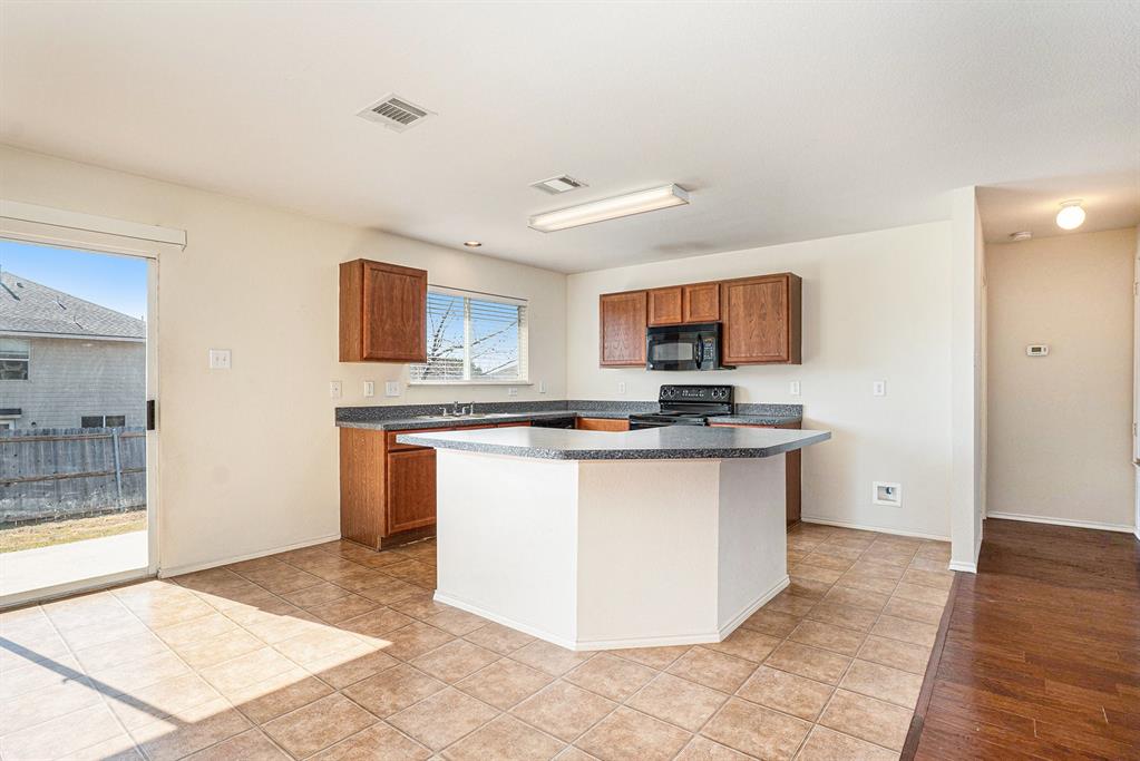 2120 Bliss Road Fort Worth, TX 76177 - Photo 10 of 25 Kitchen with dark countertops, wood finish cabinetry, and a kitchen island