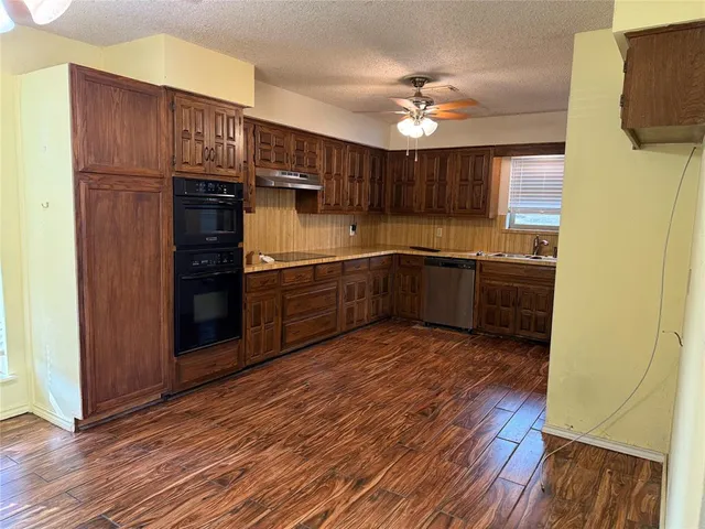 a kitchen with stainless steel appliances a sink cabinets and wooden floor