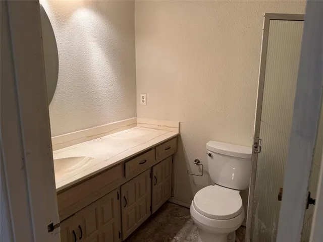 a bathroom with a granite countertop toilet and a sink