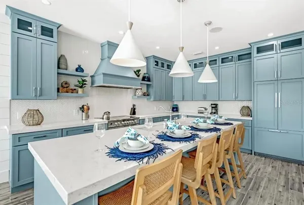 a kitchen with stainless steel appliances granite countertop a sink a stove a dining table and chairs