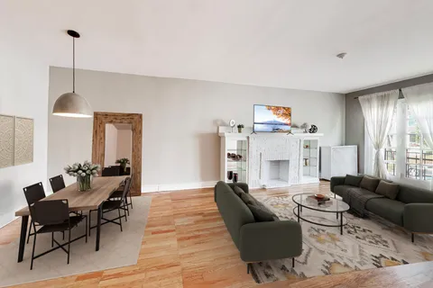 a living room with furniture kitchen view and a wooden floor