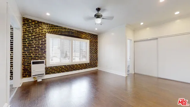 a view of an empty room with a window and wooden floor