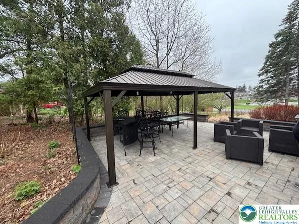 a view of a patio with a dining table and chairs under an umbrella with large trees