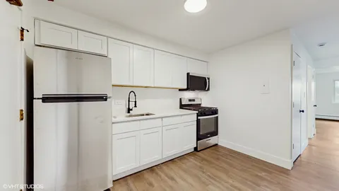 a kitchen with a refrigerator sink and white cabinets