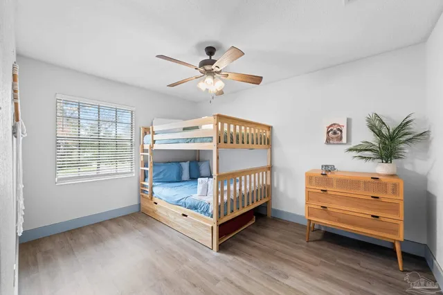 a view of an empty room with wooden floor and a ceiling fan