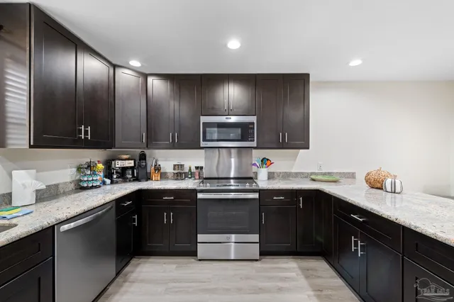 a kitchen with granite countertop kitchen island stainless steel appliances a sink and cabinets