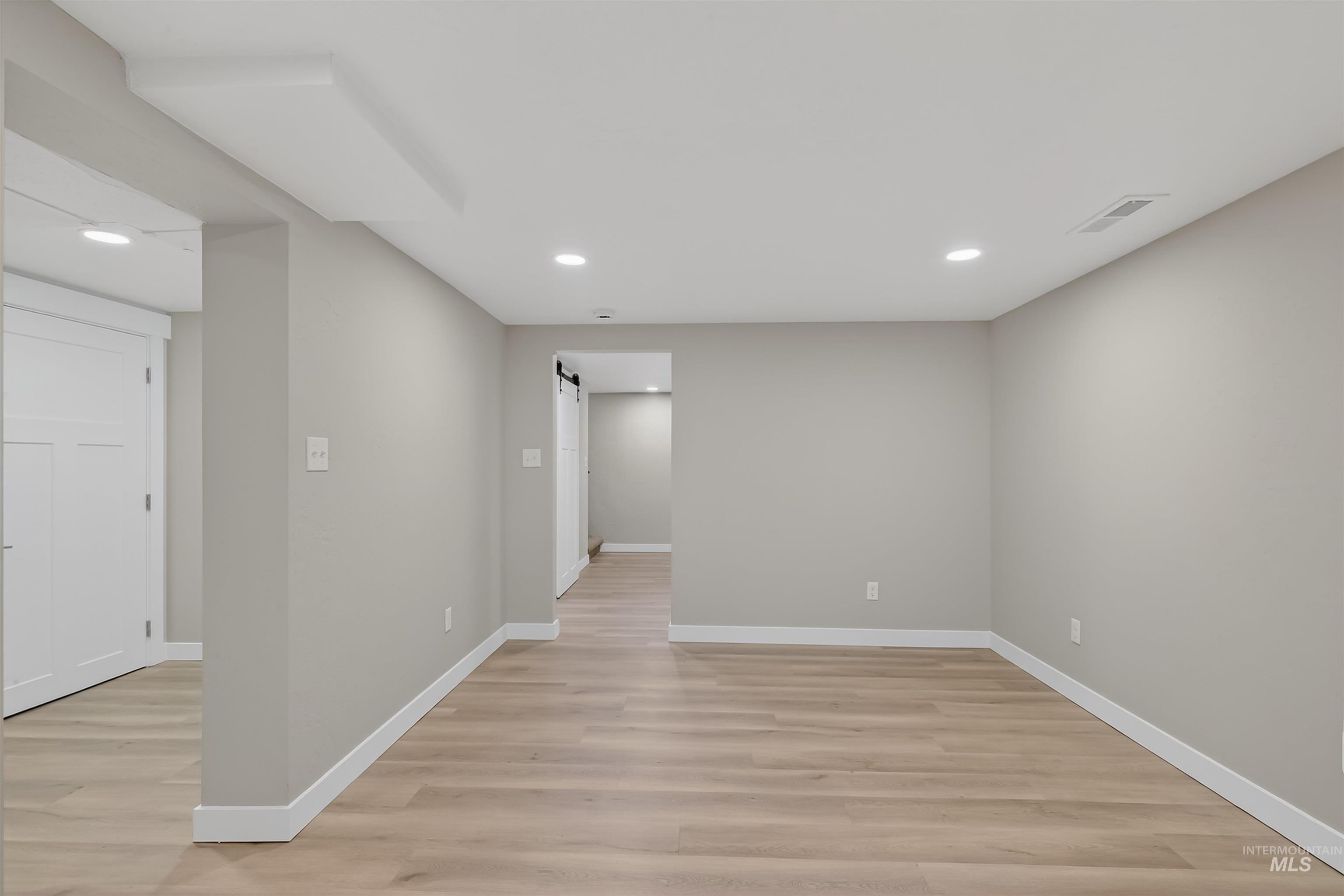 929 10th Street Clarkston, WA 99403 - Photo 24 of 43 Empty room featuring a barn door, light wood-style flooring, and recessed lighting