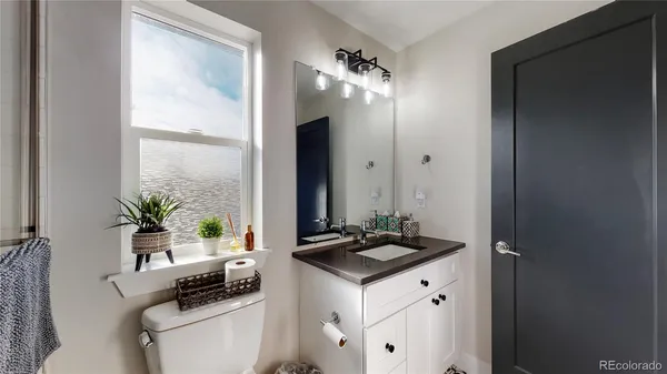 a bathroom with a granite countertop sink a toilet a mirror and a window