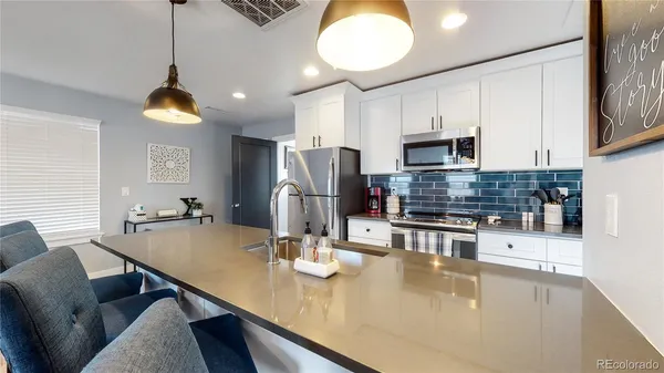 a kitchen with stainless steel appliances kitchen island granite countertop a table chairs and a refrigerator