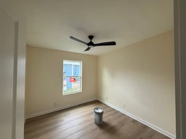 an empty room with windows and ceiling fan