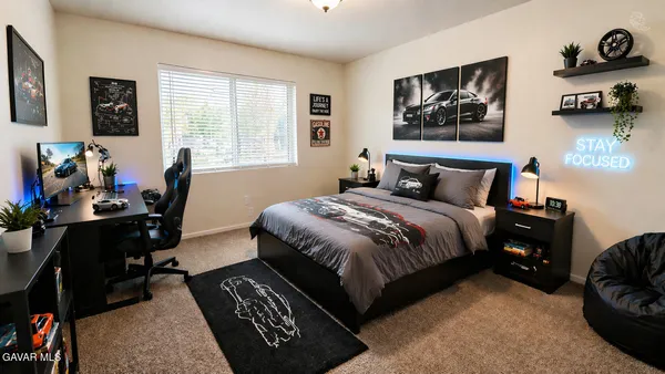 a bedroom with a bed a workstation with paintings on the wall and a window