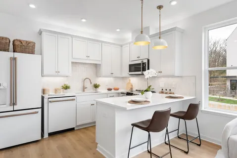 a kitchen with stainless steel appliances granite countertop a refrigerator a sink dishwasher a stove a dining table and chairs with wooden floor