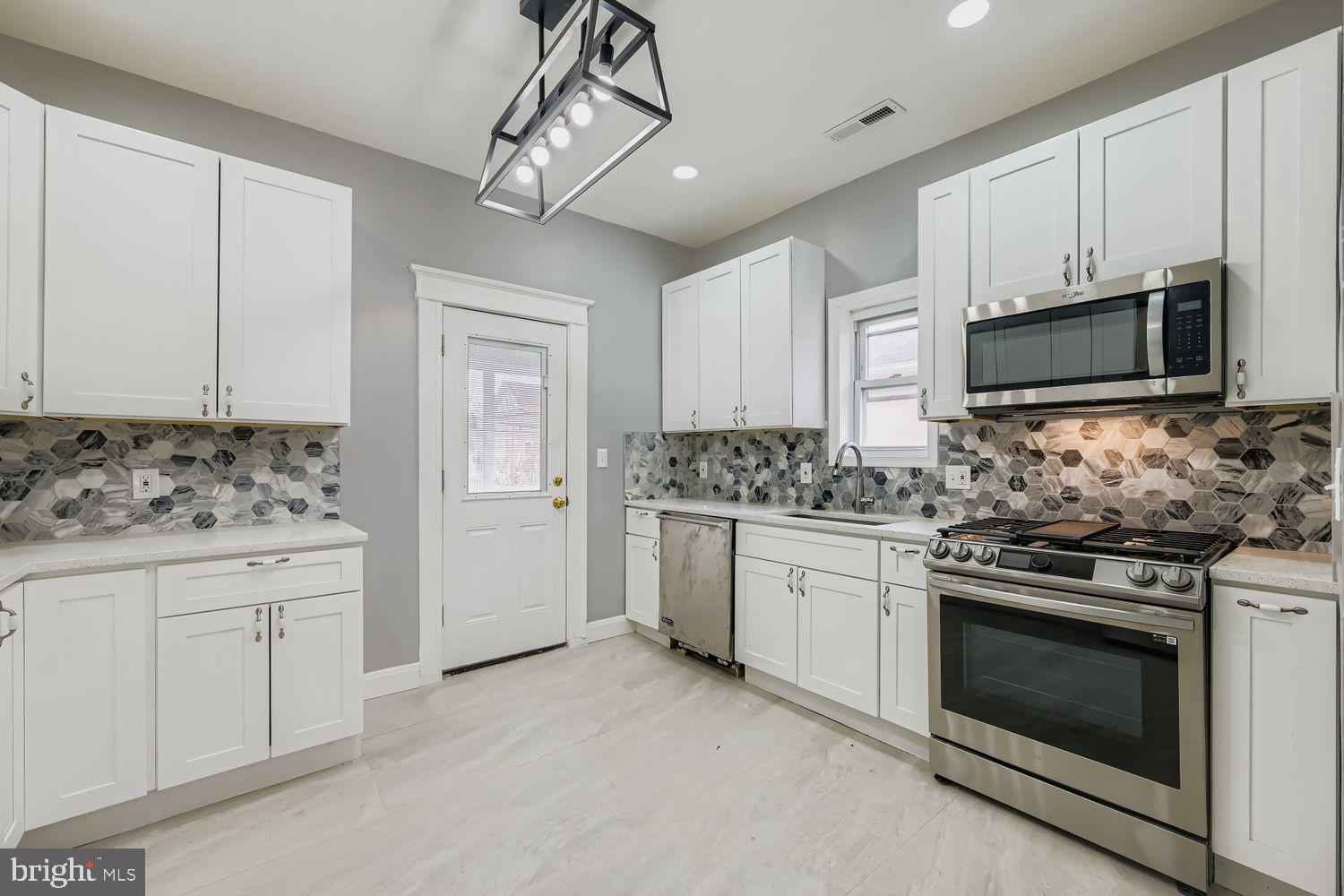 4111 Penhurst Avenue Baltimore, MD 21215 - Photo 12 of 39 a kitchen with granite countertop white cabinets white stainless steel appliances and a sink