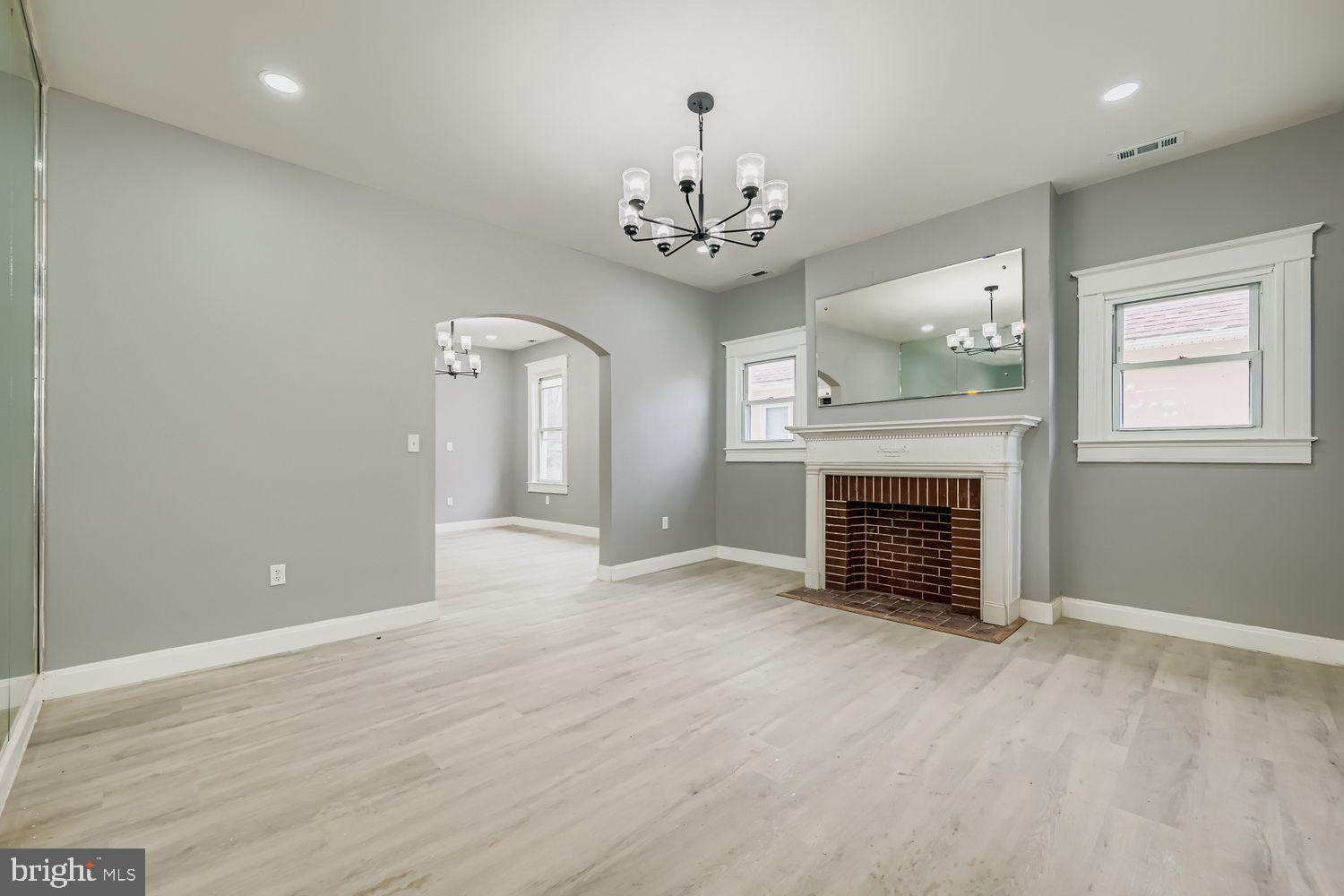 4111 Penhurst Avenue Baltimore, MD 21215 - Photo 4 of 39 an empty room with a fireplace and chandelier