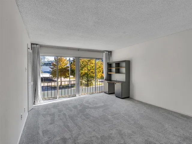 an empty room with floor to ceiling window and an outdoor view
