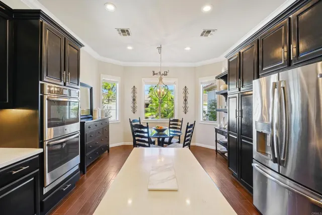a kitchen with a dining table chairs sink and wooden floor