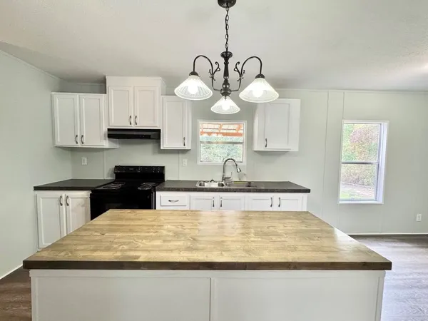 a kitchen with kitchen island granite countertop a sink a counter space and cabinets