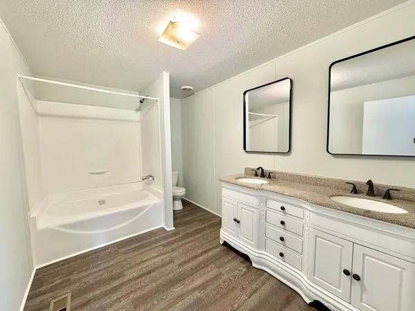 a bathroom with a tub a double vanity sink and mirror