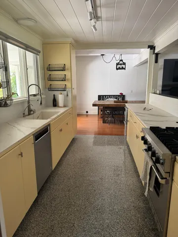 a kitchen with stainless steel appliances a sink dishwasher stove and white cabinets