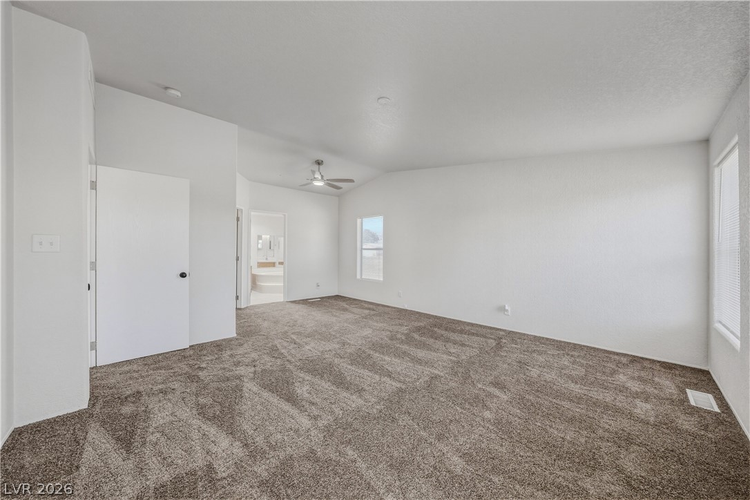 1890 West Dyer Road Pahrump, NV 89048 - Photo 19 of 40 This primary bedroom offers plush carpeting, a ceiling fan, and ample natural light.