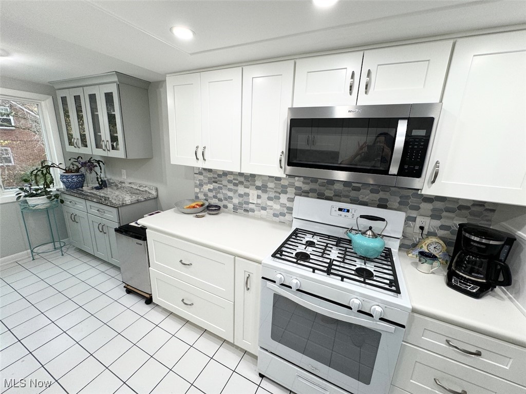 3701 Mayfield Road, Unit 207 Cleveland, OH 44121 - Photo 12 of 30 Kitchen featuring decorative backsplash, white gas stove, and white cabinets