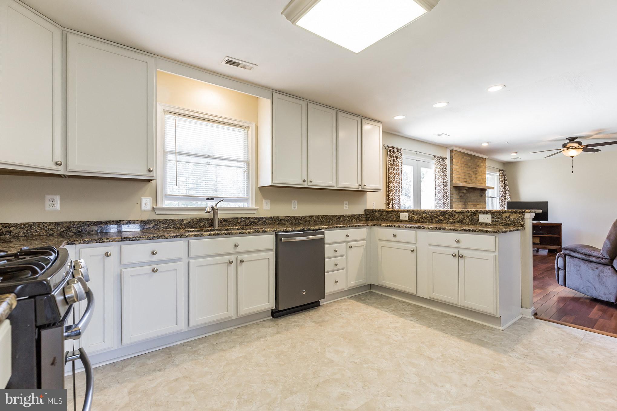 3142 Soper Road Huntingtown, MD 20639 - Photo 4 of 30 a kitchen with granite countertop sink window and white cabinets
