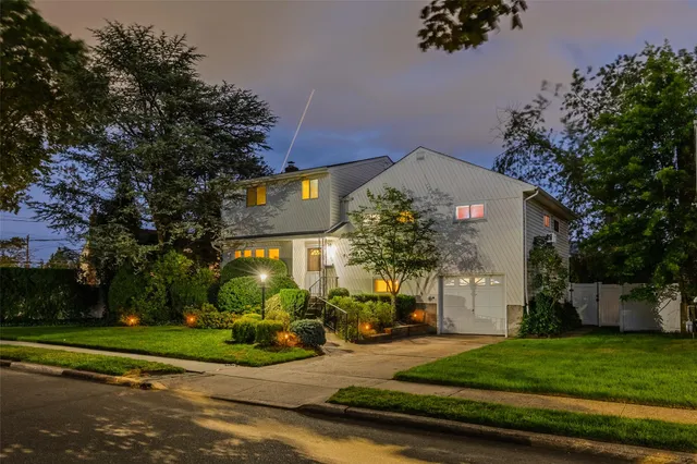 a front view of a house with a yard and a garden