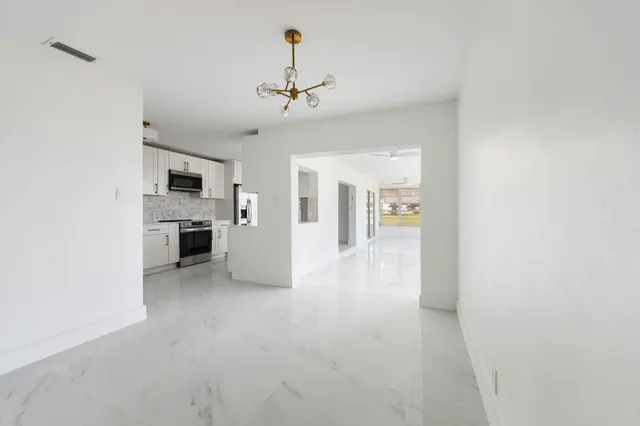a view of a kitchen with a sink and dishwasher a refrigerator with white cabinets