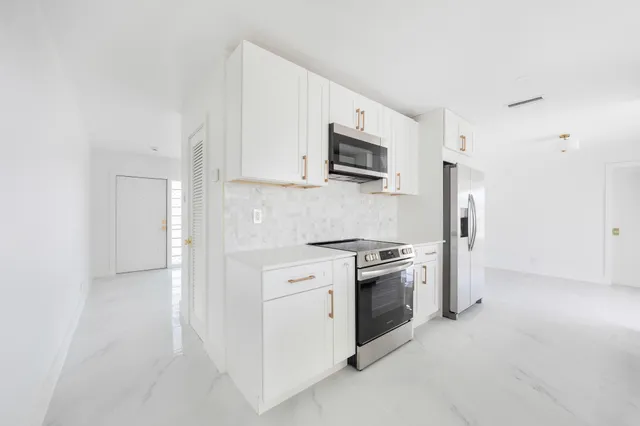 a kitchen with white cabinets and stainless steel appliances