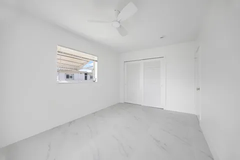 an empty room with windows and ceiling fan