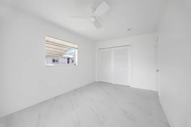 an empty room with windows and ceiling fan