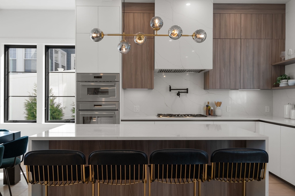 49 Ripley Street Newton, MA 02459 - Photo 6 of 32 a kitchen with granite countertop a stove and a wooden cabinets