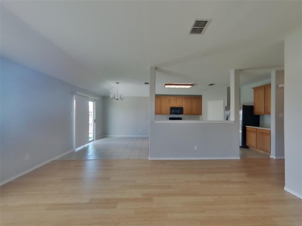 216 Rambling Way Forney, TX 75126 - Photo 2 of 22 a view of an empty room with wooden floor and a kitchen