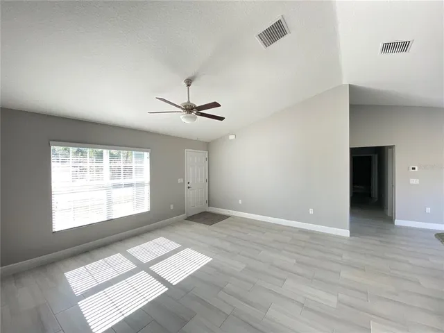 a view of an empty room with window and wooden floor
