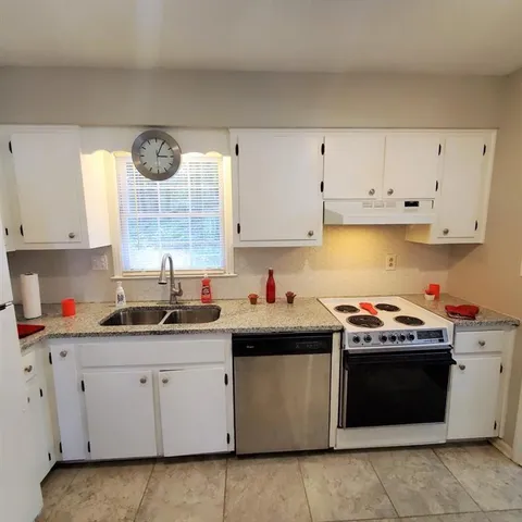 a kitchen with cabinets appliances a sink and a window