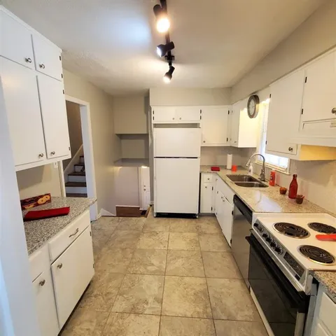 a kitchen with a refrigerator and white cabinets