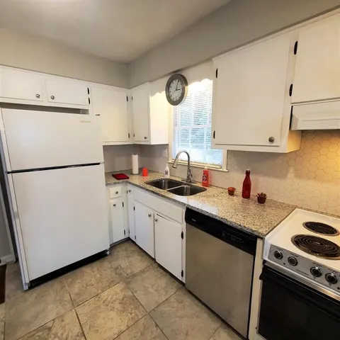 a kitchen with cabinets appliances a sink and a window