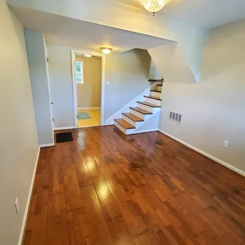 a view of an empty room with wooden floor and stairs
