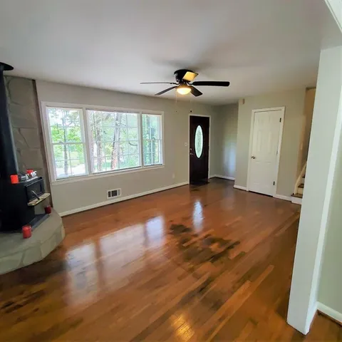 a view of an empty room with a window and wooden floor
