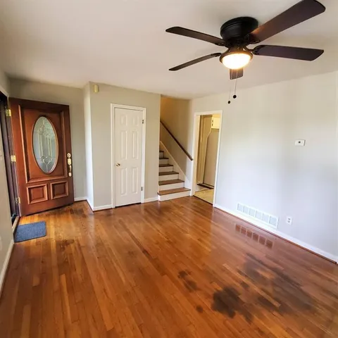 a view of an empty room with a window and wooden floor