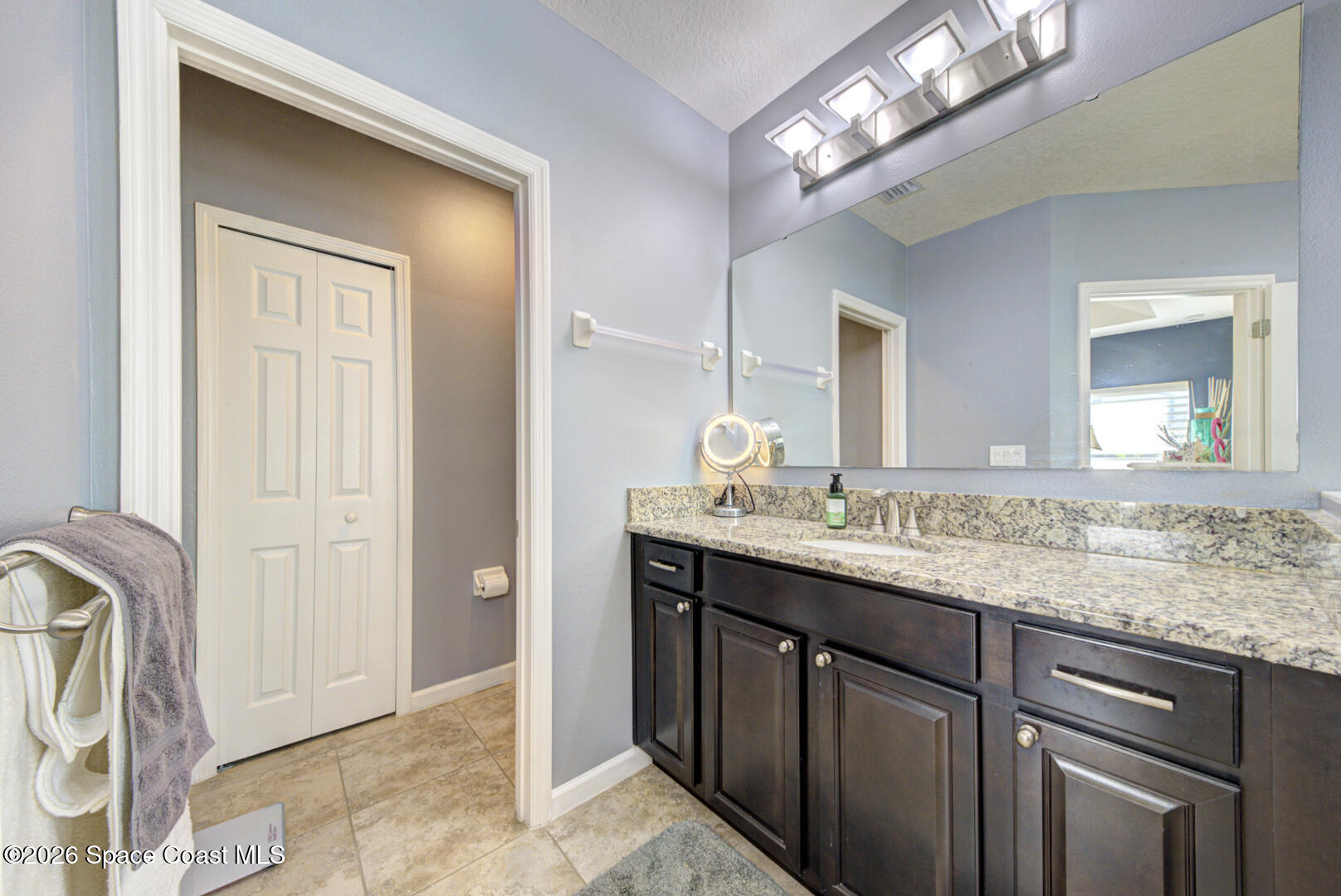 2975 Louetta Circle Melbourne, FL 32901 - Photo 19 of 44 a bathroom with a granite countertop sink a light fixture and a mirror