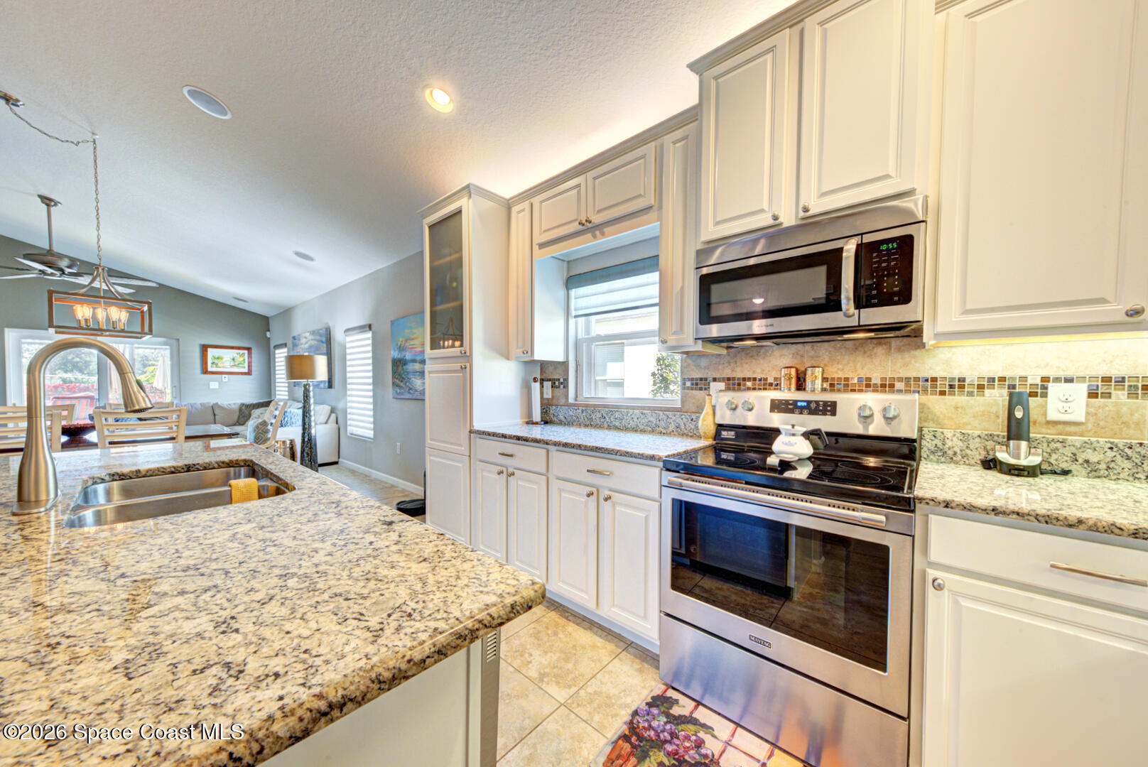 2975 Louetta Circle Melbourne, FL 32901 - Photo 4 of 44 a kitchen with stainless steel appliances granite countertop a stove top oven a sink dishwasher and microwave with wooden floor