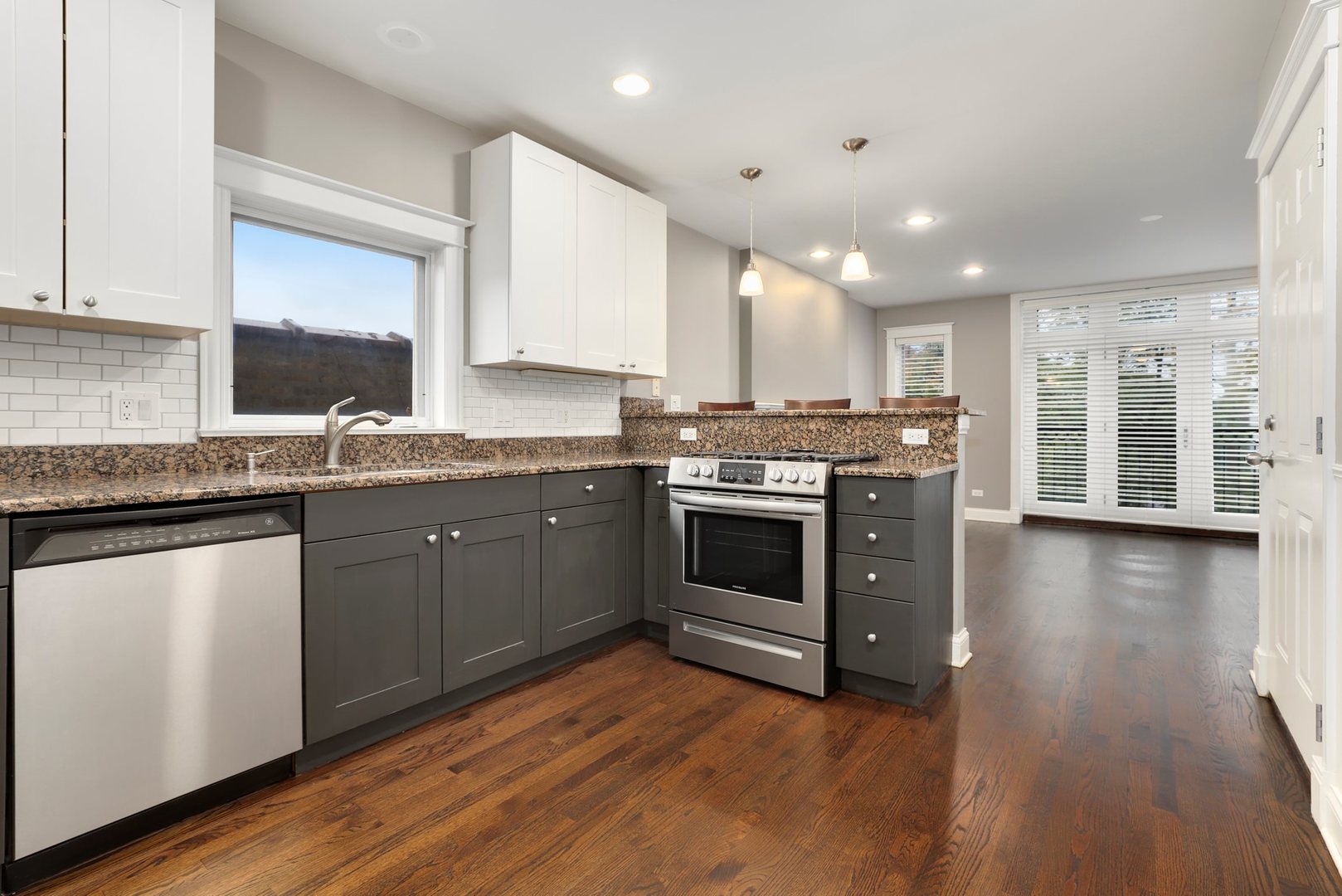3211 North Racine Avenue, Unit 2 Chicago, IL 60657 - Photo 10 of 22 a kitchen with stainless steel appliances granite countertop a stove a sink dishwasher a refrigerator white cabinets and wooden floor next to a window