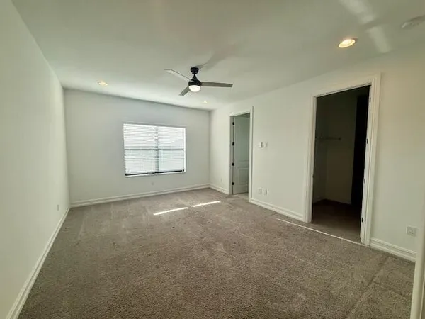an empty room with windows and ceiling fan