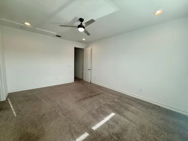 an empty room with windows and ceiling fan