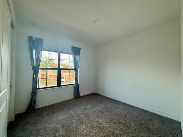an empty room with a window and ceiling fan