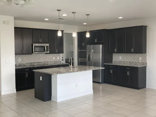 a large kitchen with a large counter top stainless steel appliances and cabinets